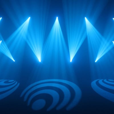 Blue stage lighting with patterned gobo projections creates a dynamic atmosphere at an indoor event or concert.