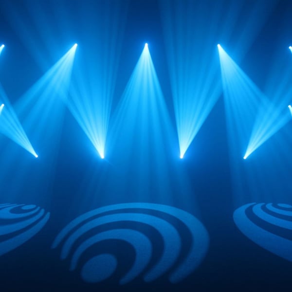 Blue stage lighting with patterned gobo projections creates a dynamic atmosphere at an indoor event or concert.