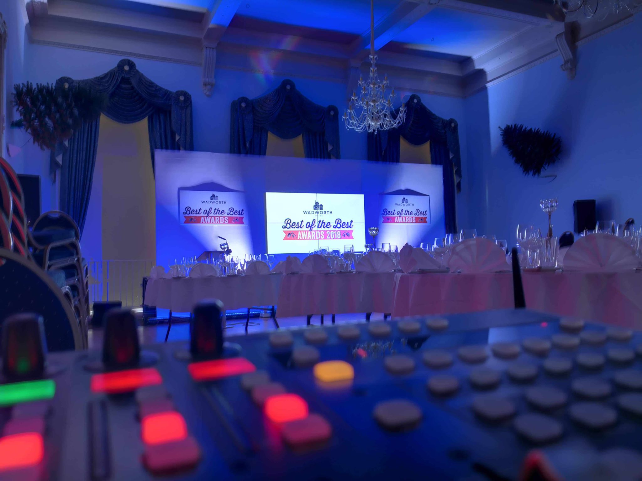 Stage setup with AV equipment for a corporate awards night, featuring seating and lit backdrop screens in an elegant venue.