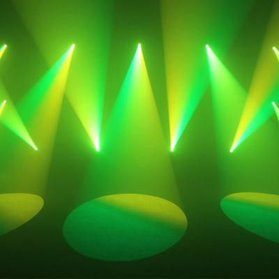Green and yellow stage lights casting beams and circles on the floor, creating a dynamic event atmosphere.