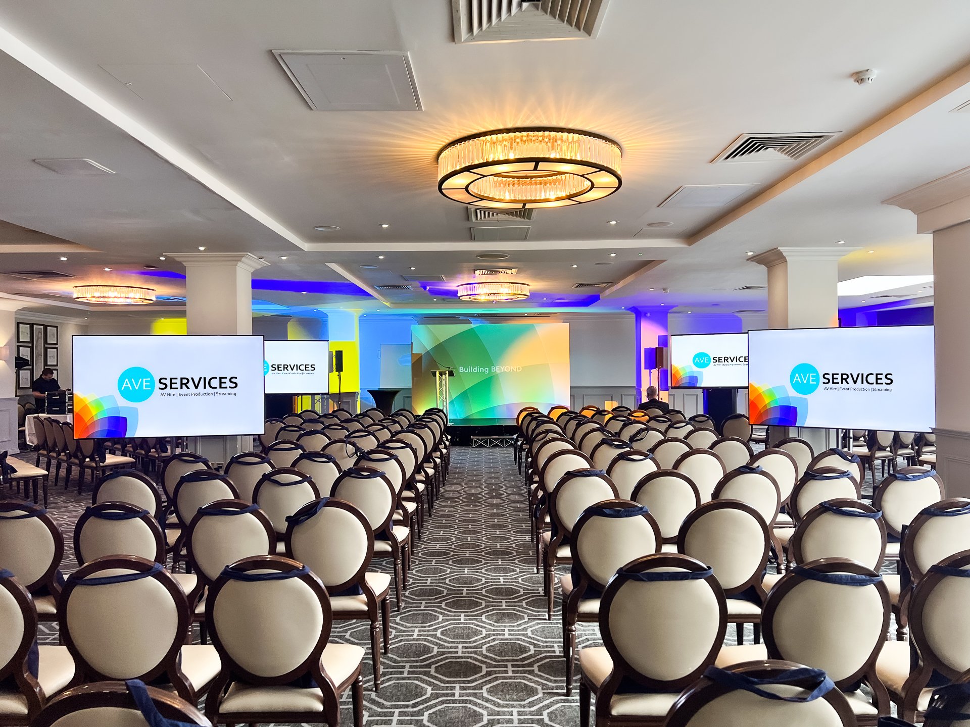 Conference, large audience, event, events, large events, large screens, 85" screen, 86" screen, PA system, wireless microphone, speakers, RCF, handheld microphone, lapel microphone. lighting, backdrop, staging, lectern, stage, Wokefield Estate, Berkshire, Networking event, Set, comfort monitor, AV hire, Audio visual equipment, AVE Services