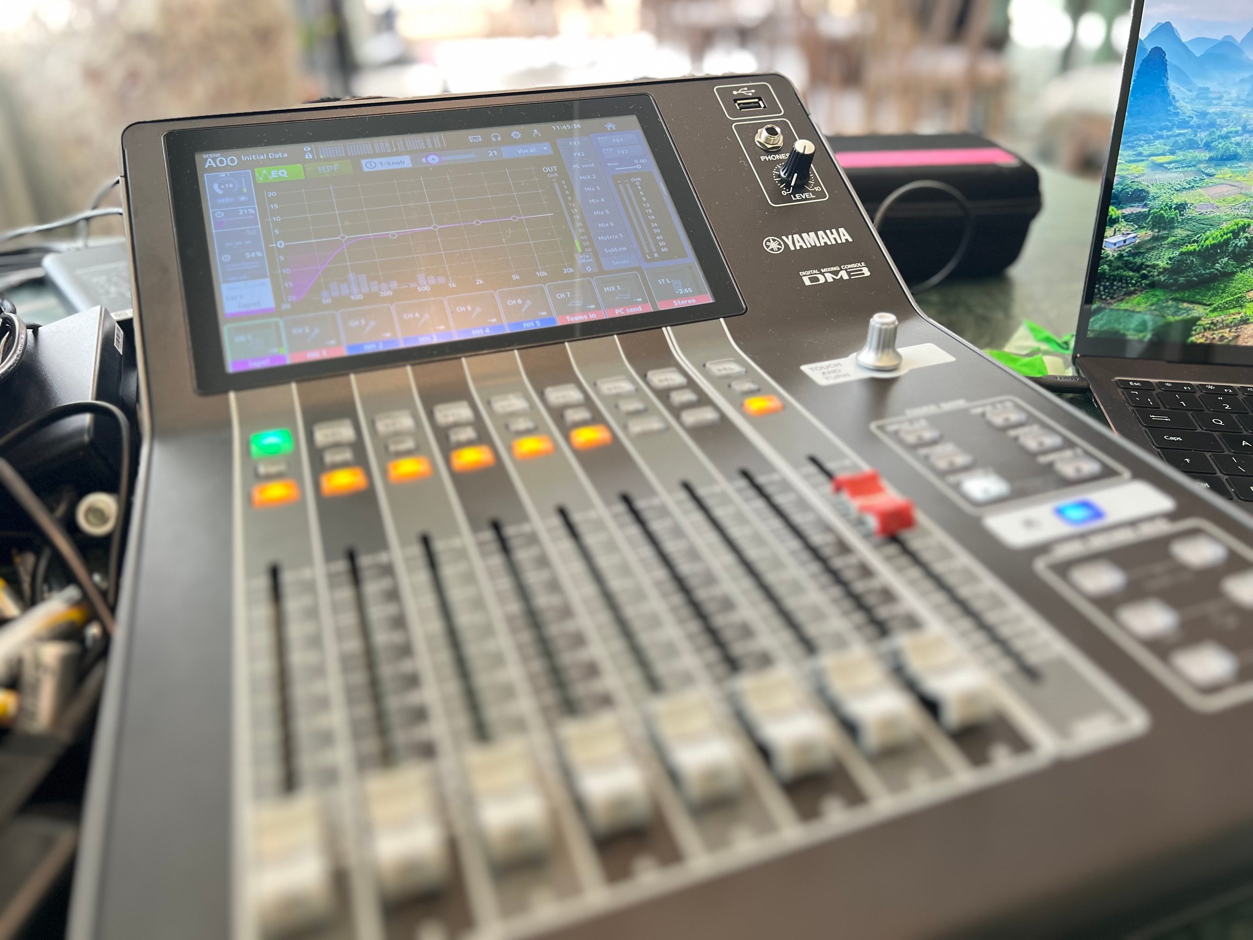Audio mixing console with digital interface, featuring sliders and control knobs, used for live event sound management.