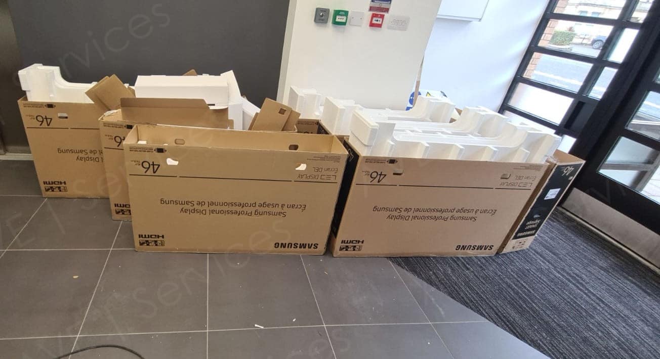 Empty AV equipment boxes and packaging materials in a venue lobby, ready for setup or disposal.