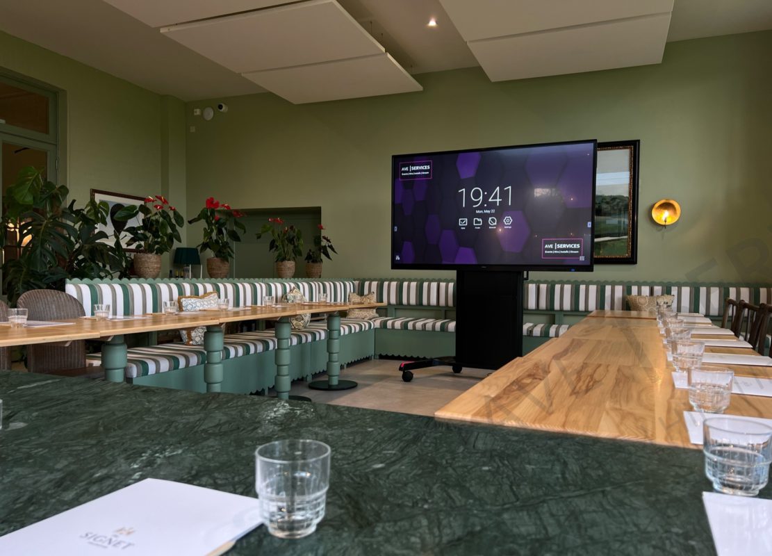 Conference room setup with a large AV screen, wooden tables, and seating. Ideal for corporate meetings and presentations.